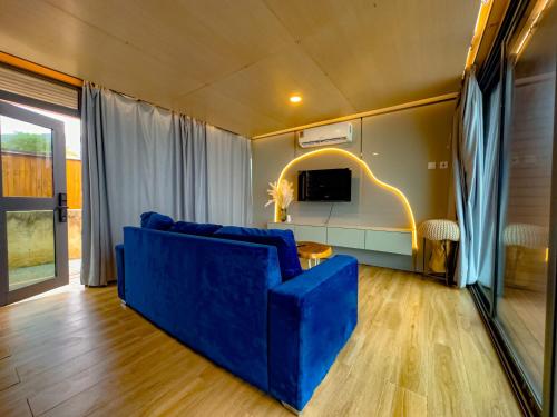 a living room with a blue couch and a tv at Akoma in Kokrobite
