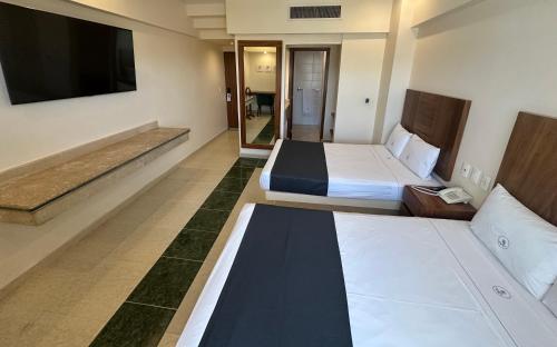 a hotel room with two beds and a flat screen tv at Hotel Real Del Sol in Guadalajara