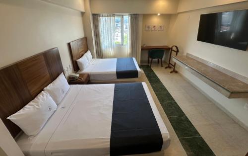 a hotel room with two beds and a flat screen tv at Hotel Real Del Sol in Guadalajara
