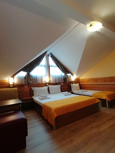 a bedroom with two beds and a couch and windows at Boutique Guest House IKONOMOV in Bansko