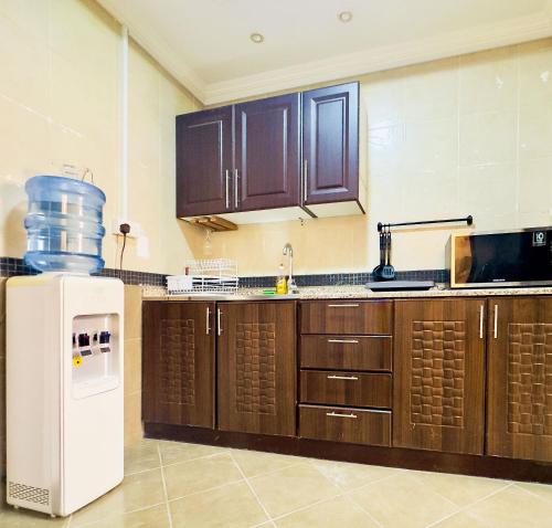 a kitchen with brown cabinets and a white refrigerator at Mid-Century Modern Comfort 1BR in Abu Dhabi