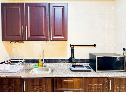 a kitchen counter with a microwave and a sink at Mid-Century Modern Comfort 1BR in Abu Dhabi