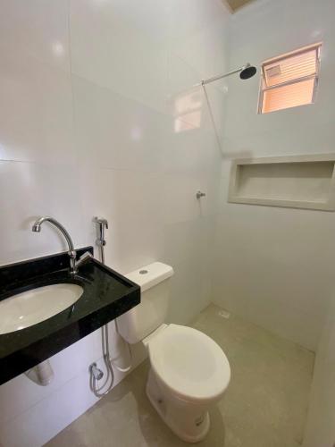 a white bathroom with a toilet and a sink at Apto Flat in Belém
