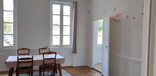 Centre ville Angouleme في أنغوليم: غرفة طعام بها طاولة وكراسي ونوافذ