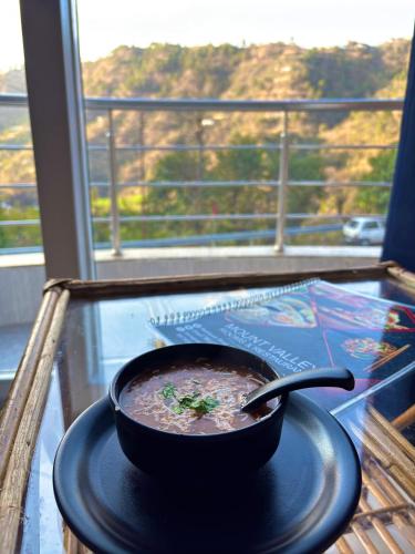 a bowl of soup on a glass table in front of a window at Mount Valley in Chamba