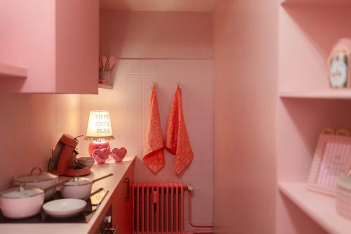 a small kitchen with pink walls and white tiles at The Rozette Experience in Ostend
