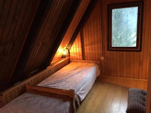 a bed in a room with a window in a cabin at Romantic Forest House Tršće in Tršće