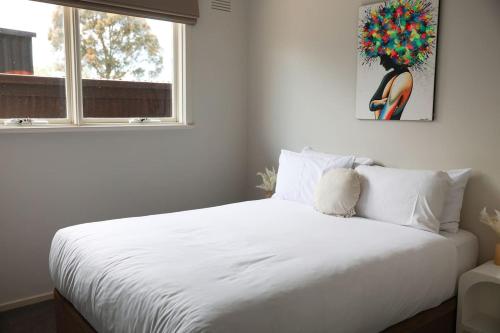 Grove Retreat With Pool, Sauna and Family Fun في Grovedale: غرفة نوم بسرير أبيض ونافذة