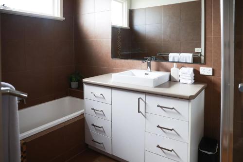 Grove Retreat With Pool, Sauna and Family Fun في Grovedale: حمام مع حوض استحمام ومغسلة بيضاء