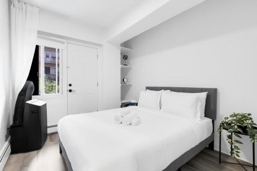 a white bedroom with a large bed and a window at The Sherbrooke Suite in Montreal