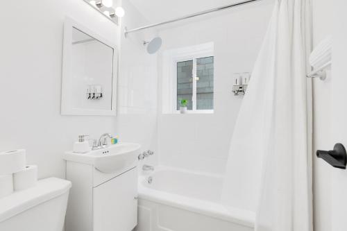 a white bathroom with a sink and a shower at The Sherbrooke Suite in Montreal