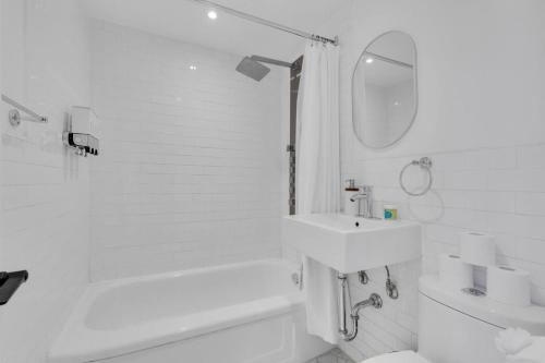 a white bathroom with a sink and a bath tub at The Sherbrooke Suite 99 in Montreal