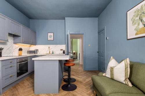 Una cocina con paredes azules y un sofá y una mesa. en Modern 1-Bed Retreat by Stirling Train Station, en Stirling