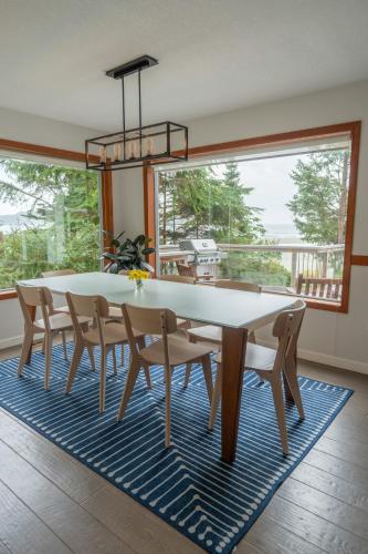 a dining room with a table and chairs on a rug at Chesterman on the Point - Beachfront in Tofino