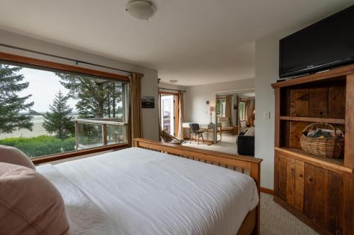 ein Schlafzimmer mit einem Bett und einem großen Fenster in der Unterkunft Chesterman on the Point - Beachfront in Tofino