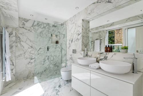 a bathroom with two sinks and a marble wall at Buckingham & Lloyds in London