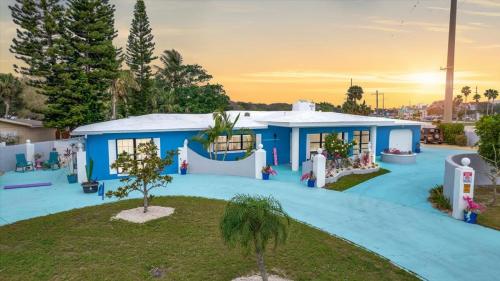 a blue house with a tree in front of it at The Leon Lane Oasis w Pool Fire Pit Steps to the Beach in Cape Canaveral