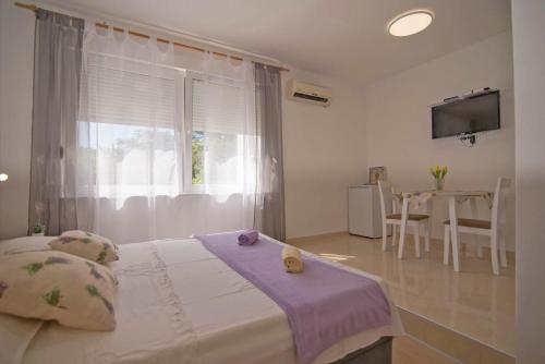 ein Schlafzimmer mit einem Bett mit Fenster und einem Tisch in der Unterkunft Complex 21 in Mali Lošinj