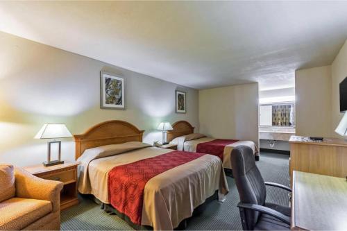 a hotel room with two beds and a chair at Eco Inn Suites by Hotel O Baytown in Baytown