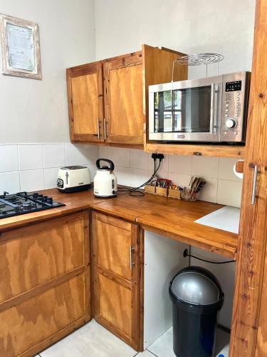 a kitchen with wooden cabinets and a microwave at De Valk & Tak Manor in Bloemfontein