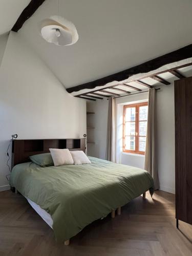ein Schlafzimmer mit einem grünen Bett und einem Fenster in der Unterkunft Le Nid Bellifontain - Appartement Confort - Centre in Fontainebleau