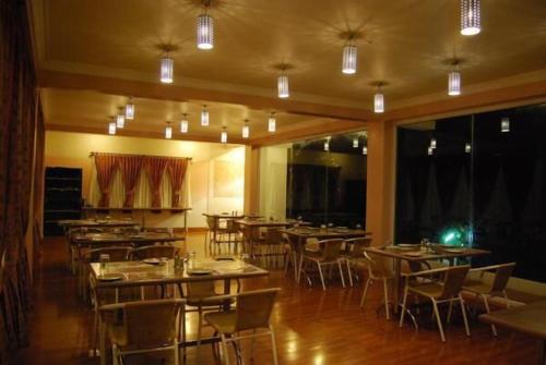 Un comedor con mesas, sillas y luces. en LMS Palve Sugavasam, en Ooty