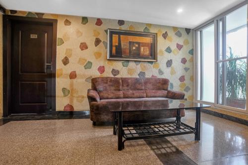 Una sala de estar con un sofá de cuero y una mesa. en Super Townhouse Divya Palace, en Indore