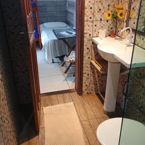 a bathroom with a sink and a bed in a room at Pousada Marambaia Café - Praiana, econômica, Com café da manhã, piscina e hidromassagem ao ar livre - Frente para o mar in Barra de Guaratiba