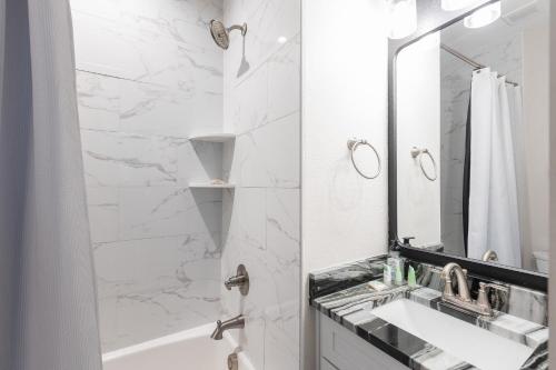 a white bathroom with a sink and a mirror at THAT House - NEW Oceanview Steps to the Beach in Kill Devil Hills