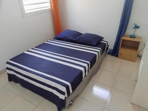 Un dormitorio con una cama con rayas azules y blancas. en Abricotier à proximité des plages du sud, en Rivière-Pilote