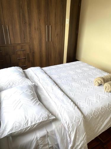 ein weißes Bett mit zwei darauf liegenden Teddybären in der Unterkunft Departamento tranquilo con terraza privada in Riobamba