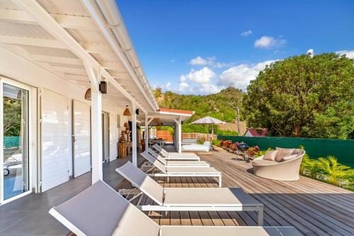 an outdoor deck with lounge chairs and tables at Villa Bohème in Terre-de-Haut