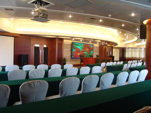 a conference room with white chairs and a screen at Kunming Golden Spring Hotel in Kunming