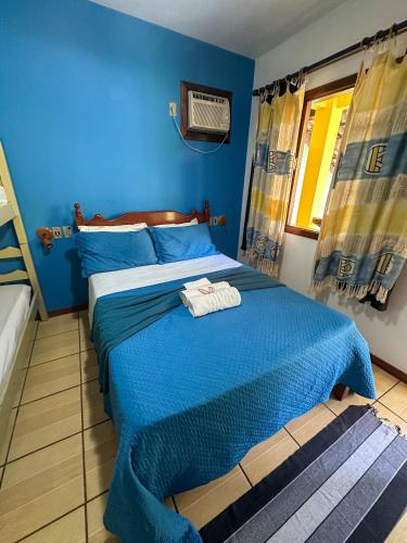 a blue bedroom with a bed with a towel on it at Buena Onda Suites in Abraão