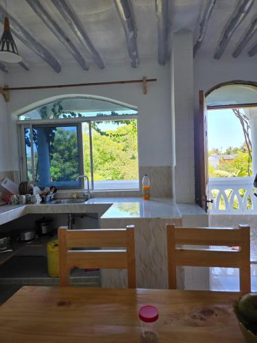 迪亚尼海滩CASA BOUGAN APARTMENTS的厨房设有2扇窗户和桌椅