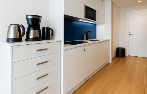 una cucina con mobili bianchi e un forno a microonde di Elite Class Sea View Aparthotel In Orbi City Batumi a Batumi