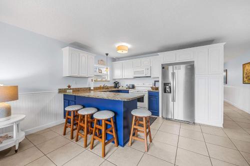 a kitchen with white cabinets and a blue island with bar stools at Oceanview Escape Private Beach Access in South Cocoa Beach