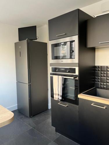una cucina con mobili neri e un frigorifero di Charmant appartement centre a Laval