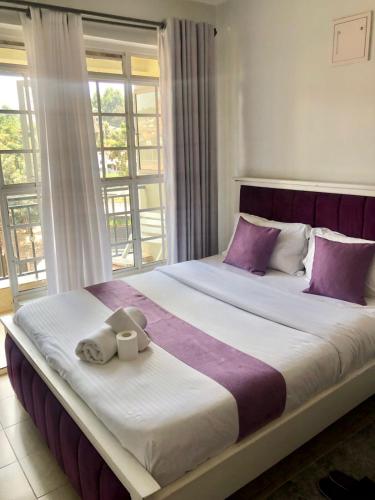 a bedroom with a large bed with purple and white pillows at Belaire BnB Ruaka 3 in Ruaka