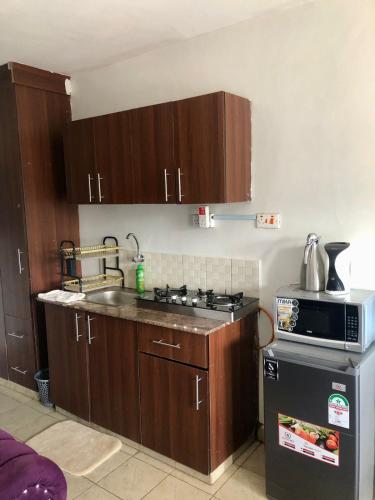 a kitchen with wooden cabinets and a stove top oven at Belaire BnB Ruaka 3 in Ruaka