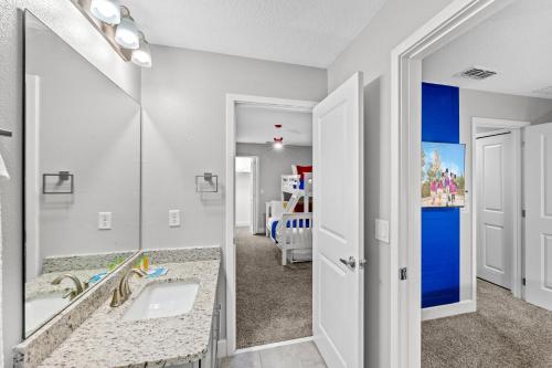 ein Badezimmer mit Waschbecken und Spiegel und ein Schlafzimmer in der Unterkunft Gated community 4BD townhouse next to Disney in Kissimmee