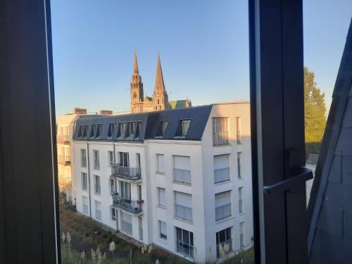 uma vista para um edifício branco a partir de uma janela em Le pied à terre em Chartres