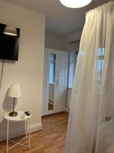 a bedroom with a white curtain and a table with a lamp at The Cotton Mill Hideaway - One Bedroom Apartment - Free Parking near Etihad Stadium & CoOp Live in Manchester