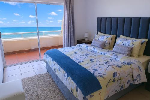 a bedroom with a bed with a view of the ocean at 606 L'esclaier Cabanas - Seaside Paradise in Amanzimtoti