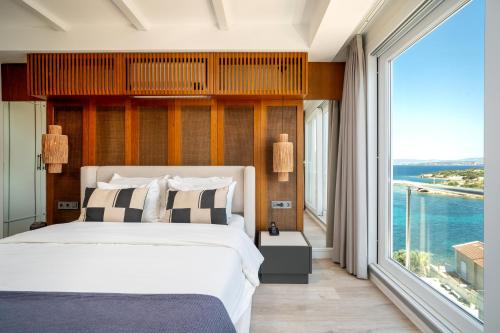 a bedroom with a large bed and a large window at Dalyan Residence & Suites in Çeşme