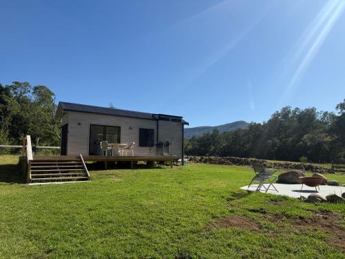 a tiny house with a porch and a deck at Ferncroft Farm Tiny Home Berry in Wattamolla