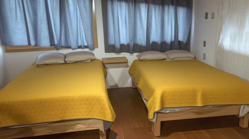 two beds in a room with yellow sheets and windows at Cabañas El Borrego in Mazamitla