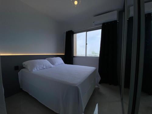 a bedroom with a white bed and a window at Congresso ou maratona, studio central, com garagem in Florianópolis