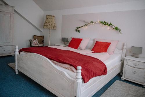 a bedroom with a large white bed with red pillows at Ferienwohnung Landliebe in Pfullendorf