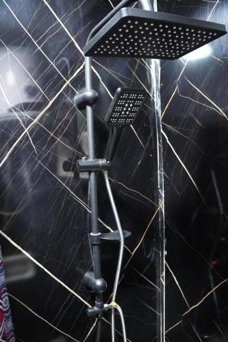 a stand up shower in a room with a black wall at Petra entrance Apartment in Petra